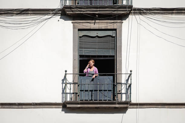 MADRID, SPAIN - AUGUST 4, 2014: Architecture of Madrid. The unknown woman came to a balcony of apartments and looks at the street. Madrid capital and the largest city of Spain.