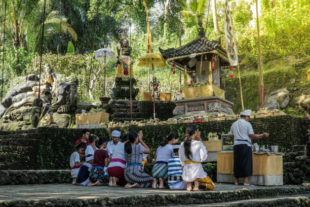 Balinese woman praying at temple in Bali, ceremony hands, offerings and incense, traditional dress