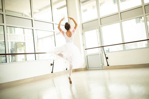 Rear view of Beautiful teenage ballet dancer in tutu  doing  ballet pirouette lively