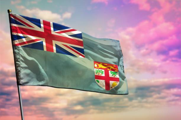 istock Fluttering Fiji flag on colorful cloudy sky background. Prosperity concept. 1135736047