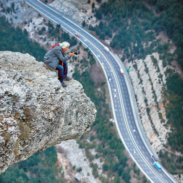 istock Man standing on cliff edge and photographing landscape 1135736735