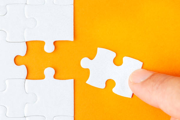 istock Hand holding piece of white puzzle on orange background 1135737027
