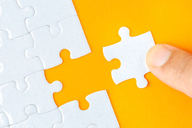 istock Hand holding piece of white puzzle on orange background 1135737028