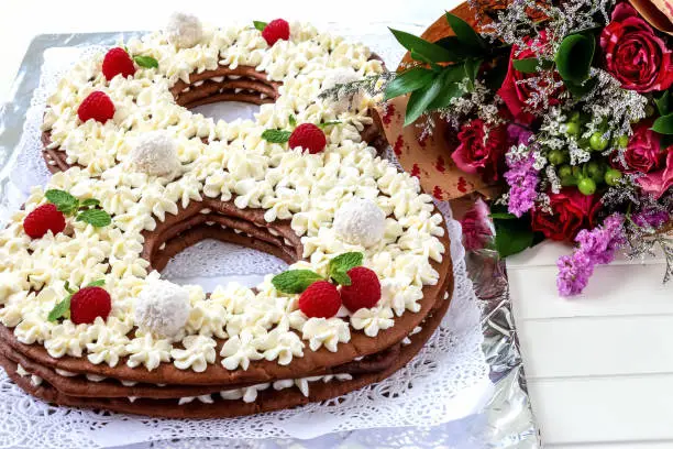 Big number cake shape of 8 decorated white creamcheese, raspberry and coconut candy. Happy birthday or womens day of 8 march concept. Top view. White wooden background.