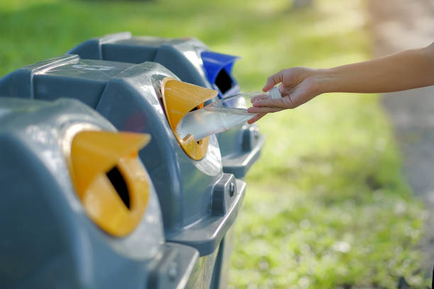 istock Close-Up Of Hand Putting Bottle In Garbage Bin 1135739956