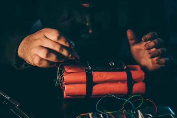 One man, masked terrorist making a dynamite in dark workshop alone.