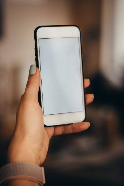 istock Lady's hands holding modern white smartphone with white empty screen 1135742862