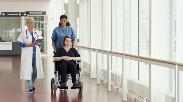 Female doctors talking with patient on wheelchair
