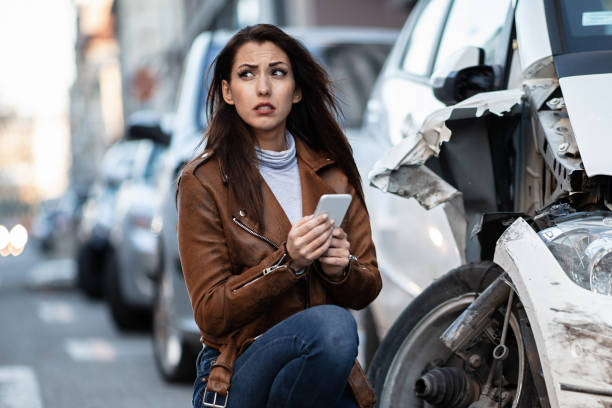 istock Young sad woman texting on cell phone after a car crash. 1135745792