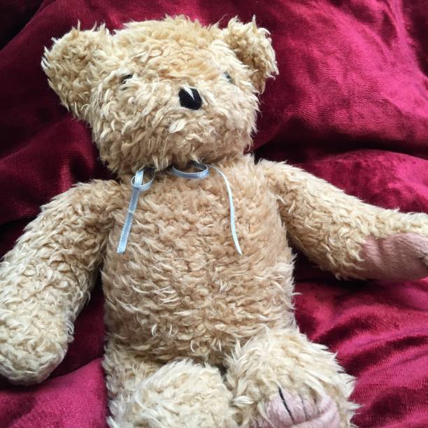 istock Teddy bear with blue ribbon tie on red velvet 1135748241