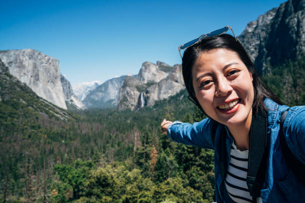 woman hiker taking selfie pointing to waterfall