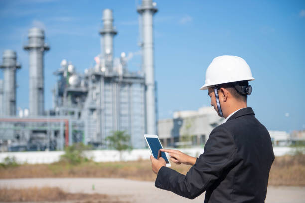 industrial engineer standing in front of a large  power plant with safety helmet with gas turbine industry plant background - building contractor engineer digital tablet construction imagens e fotografias de stock