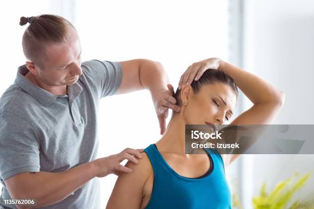 Physiotherapist Massaging Young Womans Neck Stock Photo - Download Image Now - Chiropractic Adjustment, Adult, Adults Only