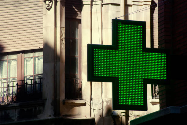 simbolo della farmacia in strada, centro storico, croce verde. - green cross foto e immagini stock