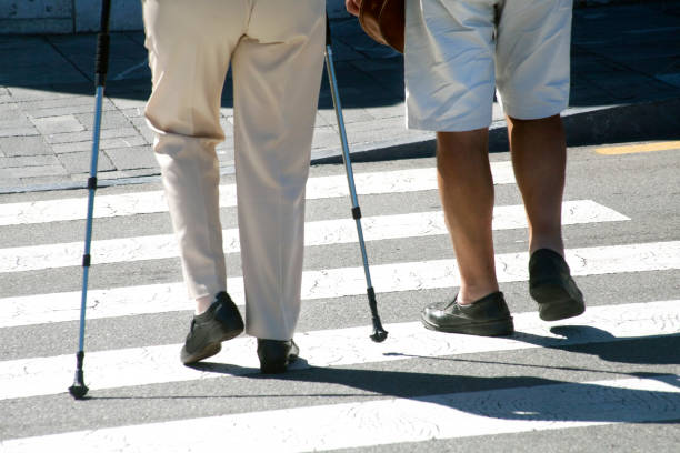 istock Two people walking on zebra crossing, one with crutches. 1135762321