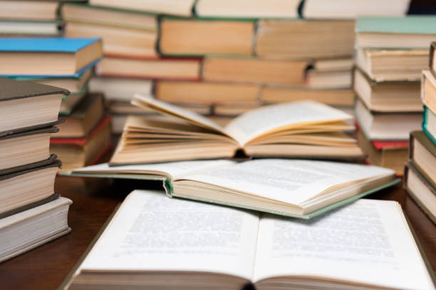 istock Education learning concept with opening book or textbook in old library, stack piles of literature text academic archive on reading desk and aisle of bookshelves in school study class room background 1135763958