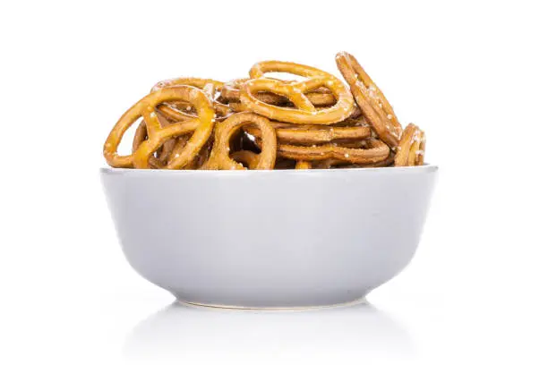 Lot of whole baked mini salted pretzels in a grey ceramic bowl isolated on white background