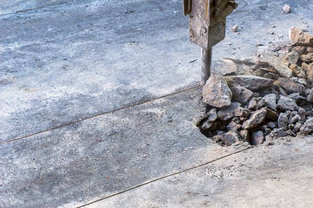 Hydraulic jackhammer crashing reinforced concrete road.