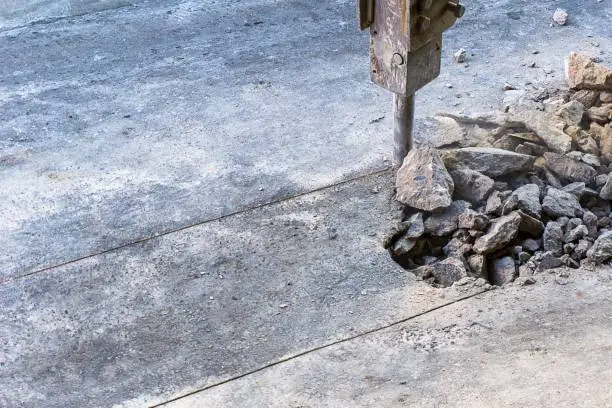 Excavator hydraulic  jackhammer crashing concrete road. and text space