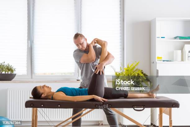 Physiotherapist Stretching Young Womans Legs Stock Photo - Download Image Now - Physical Therapy, Adult, Adults Only