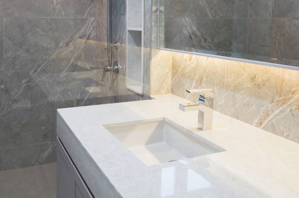 Counter top white marble with washbasin.Wall and floor beige,grey marble stone interior design of restroom or toilet background.Restroom clean design with accessories  background.