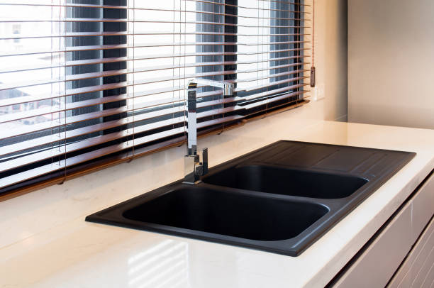 istock Modern kitchen interior in the city apartment. White marble,quartz counter top kitchen with black sink and faucet,wooden blind sunlight through the windows in the city clean and luxury design. 1135767673