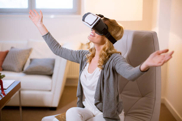 istock Joyful young woman playing computer games with virtual reality googles at home 1135767933
