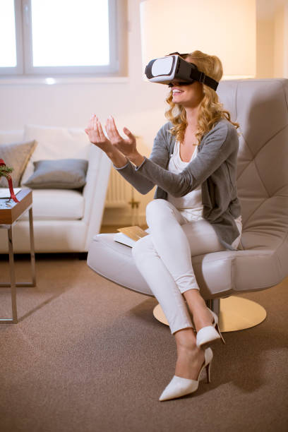 istock Joyful young woman playing computer games with virtual reality googles at home 1135767939