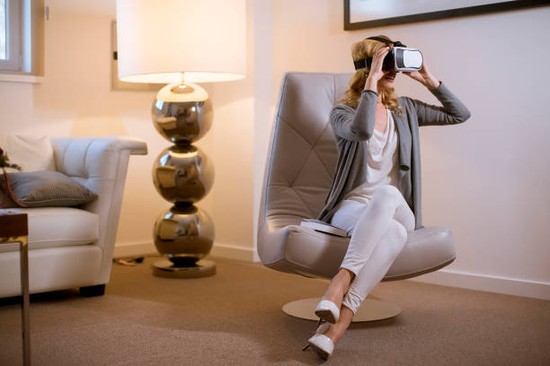 istock Joyful young woman playing computer games with virtual reality googles at home 1135767941