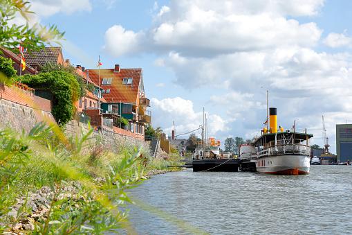 Lauenburg, Germany - August 26, 2018. Paddle steamer Kaiser Wilhelm at Lauenburg. View from the Elbe riverside path. Traditional brick houses along the shore.