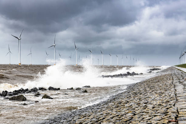istock Wind turbines in an offshore wind park during a storm with big waves hitting the shore 1135771855