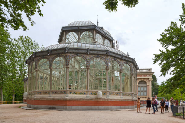 Crystal Palace in Madrid Madrid, Spain - June 07 2018: Tourists and locals gather outside the Crystal Palace (Palacio de Cristal) in the Retiro Park. Designed by architect Ricardo Velázquez Bosco, it was built in 1887 to exhibit flora and fauna from the Philippines. palacio de cristal photos stock pictures, royalty-free photos & images