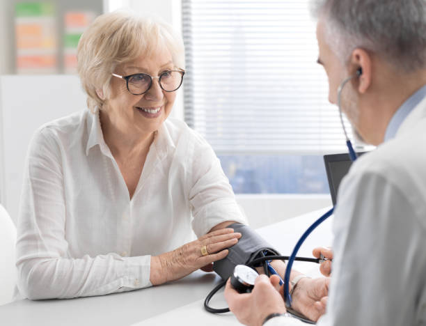 Professional doctor visiting a senior patient and measuring blood pressure using a sphygmomanometer, hypertension and healthcare concept