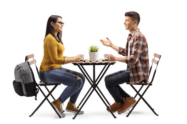 コーヒーを持ってカフェで話す男女学生 - talking chair two people sitting ストックフォトと画像