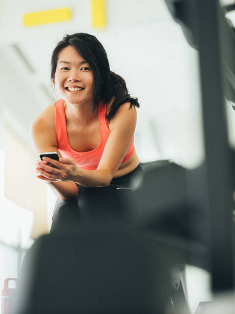istock Young Asian woman using phone in gym 1135778757