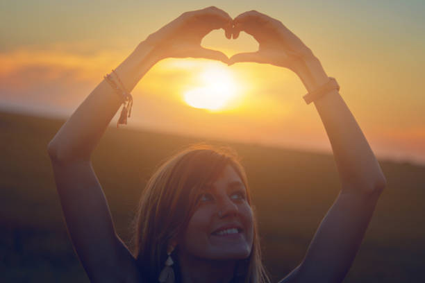 chica sosteniendo el símbolo de la forma del corazón para el amor en el atardecer/amanecer tiempo. - heart shape loneliness women praying fotografías e imágenes de stock