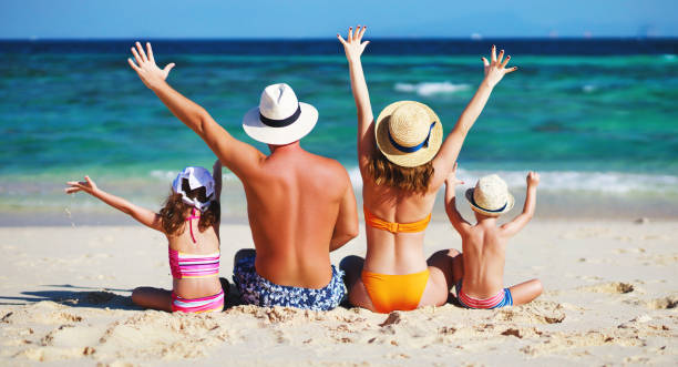 père de famille heureux, mère et enfants dos sur la plage en mer - maillot de bain photos et images de collection