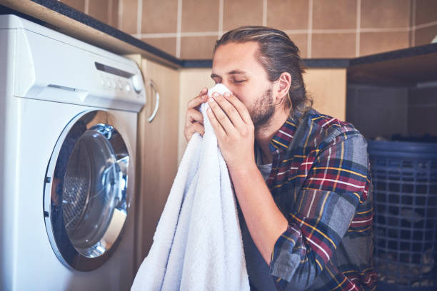 Nothing beats the smell of fresh laundry Shot of a young man smelling fresh and clean laundry at home fabric softener photos stock pictures, royalty-free photos & images