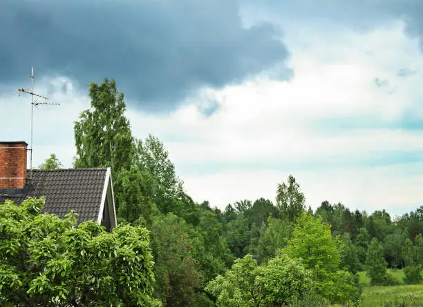 Photo of Residential area during summertime. Beautiful green vegetation, houses and rain clouds.