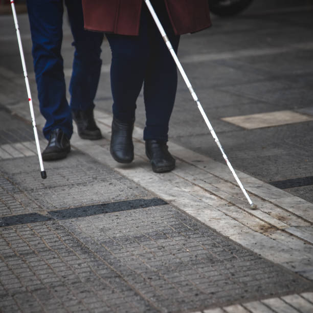 istock blind man and woman walking on the street using a white walking stick 1135786049