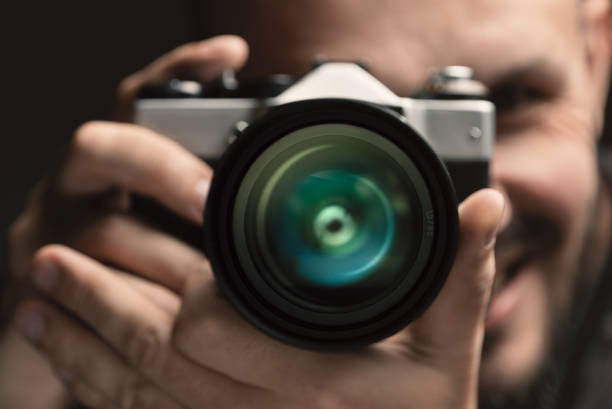 fotografo sorridente con una rara macchina fotografica. concentrati sull'obiettivo. - riflesso sullobiettivo foto e immagini stock