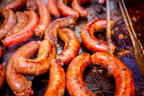 istock Turning delicious juicy sausages on barbecue plate with handle 1135787609