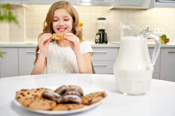 istock Pretty girl sitting at table, eating biscuits with raisins. 1135789227