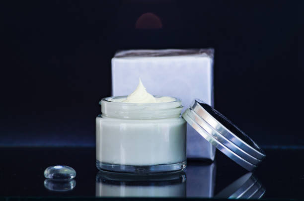 istock open jar of cream, a box on a glass table. Black  background. 1135790106
