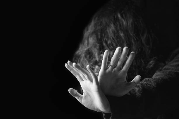 Violence against women. Black and white portrait of scared and desperate woman, focus on the hands in protective gesture Concept of a violence against women. Black and white portrait of scared and desperate woman, focus on the hands in protective gesture terrified photos stock pictures, royalty-free photos & images