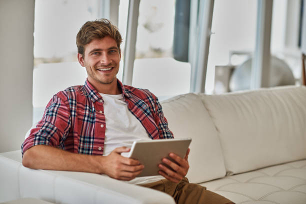 istock Young man usign digital tablet in cozy home environment 1135793349