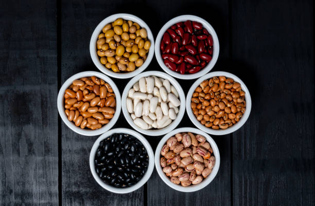 istock Seven varieties of beans inside white pot on black background. 1135796120