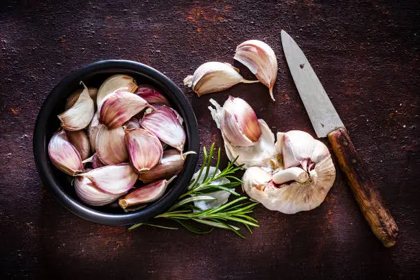 Photo of Garlic bulb and cloves shot from above on rustic brown background