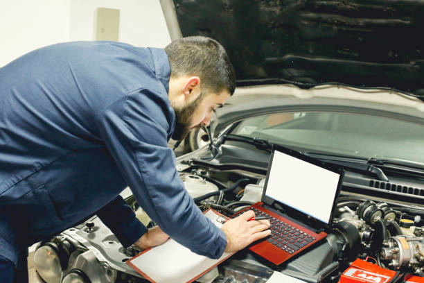 istock Handsome young auto mechanic in uniform is making notes while examining car in auto service 1135797106