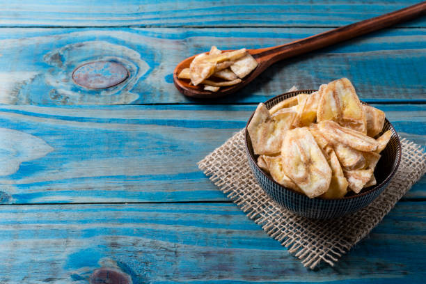 istock Banana chips inside ceramic pot over blue pine wood 1135797994